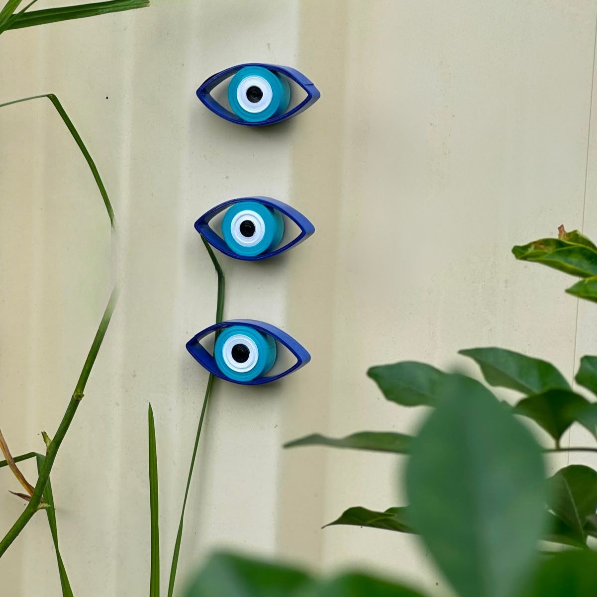 Handcrafted blue quilled paper Evil Eye magnet made from rolled paper strips with waterproof protective finish, displayed on a neutral background.
