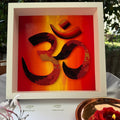 Handcrafted paper quilling OM artwork in red, orange, gold and black sunset tones, framed in white MDF