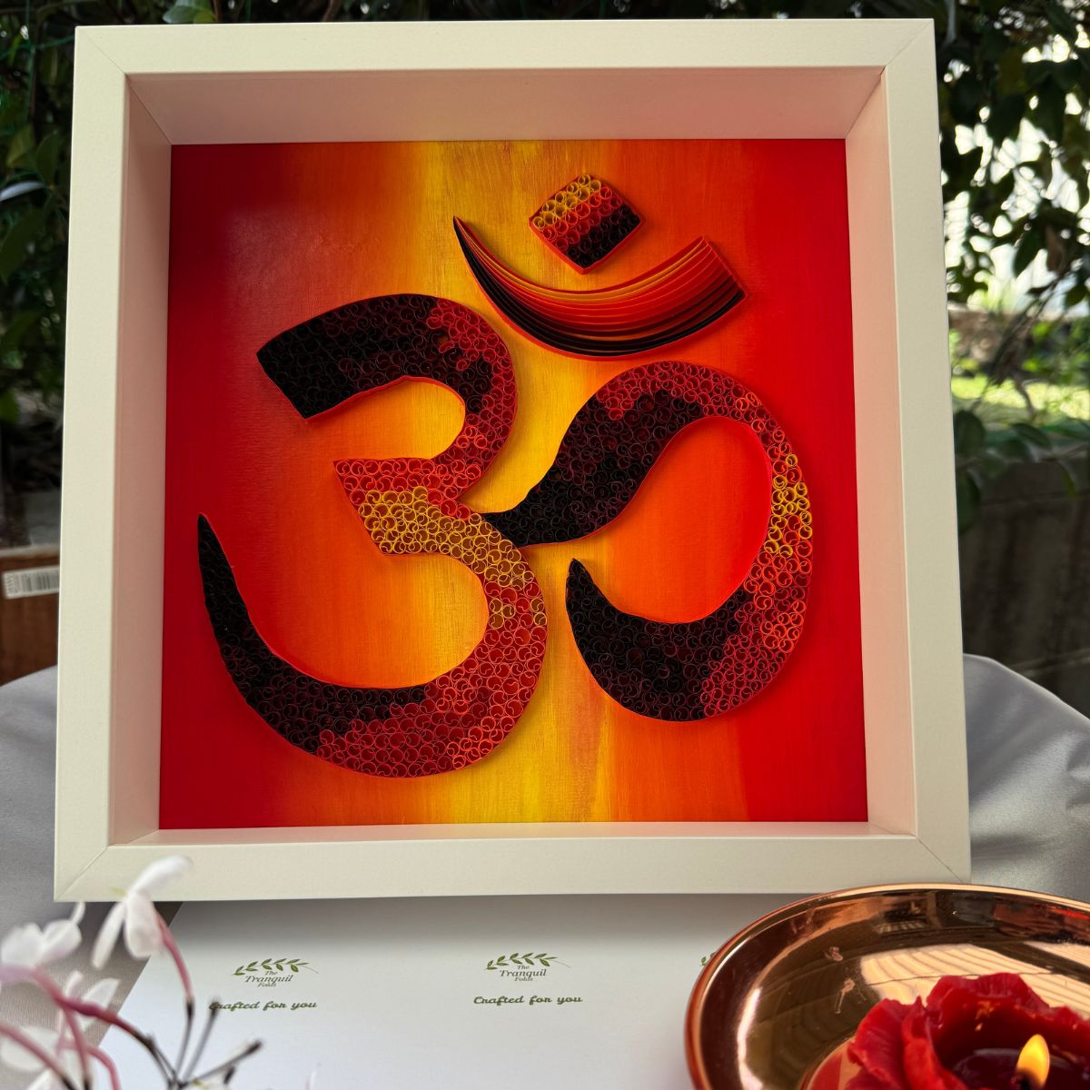 Handcrafted paper quilling OM artwork in red, orange, gold and black sunset tones, framed in white MDF