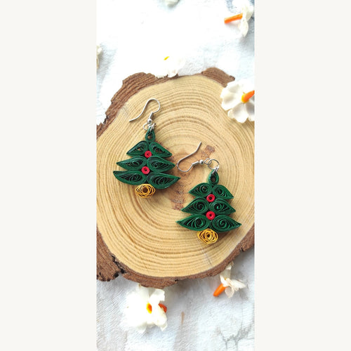 Handmade dark green Christmas tree paper quilling earrings with red decorations, golden-yellow bases and German silver hooks on a wood slice.