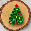 Handmade Christmas tree paper quilling fridge magnet displayed on a natural wood slice.