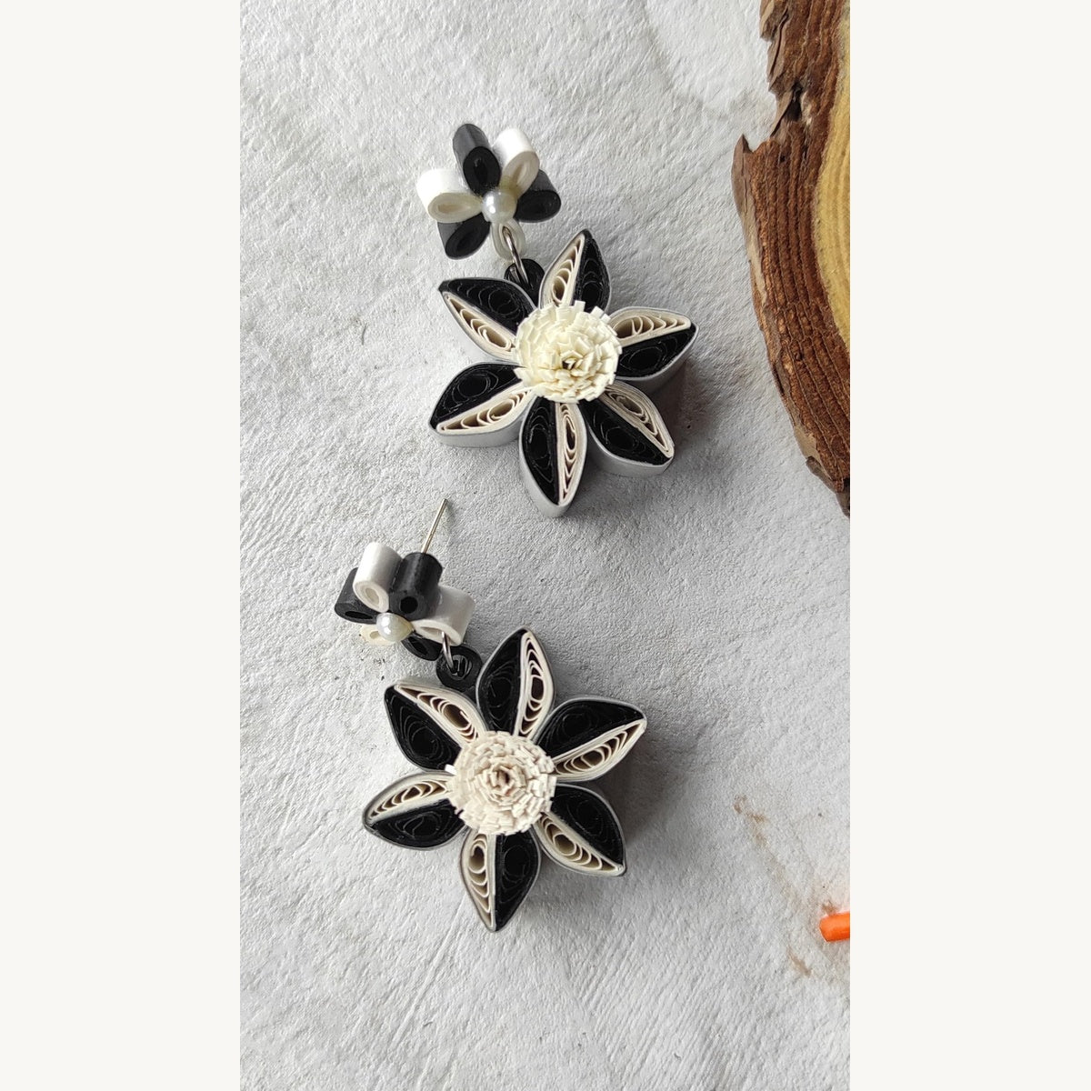 Handcrafted black and white paper quilling flower stud drop earrings with two-tone petals and pearl-look accents.