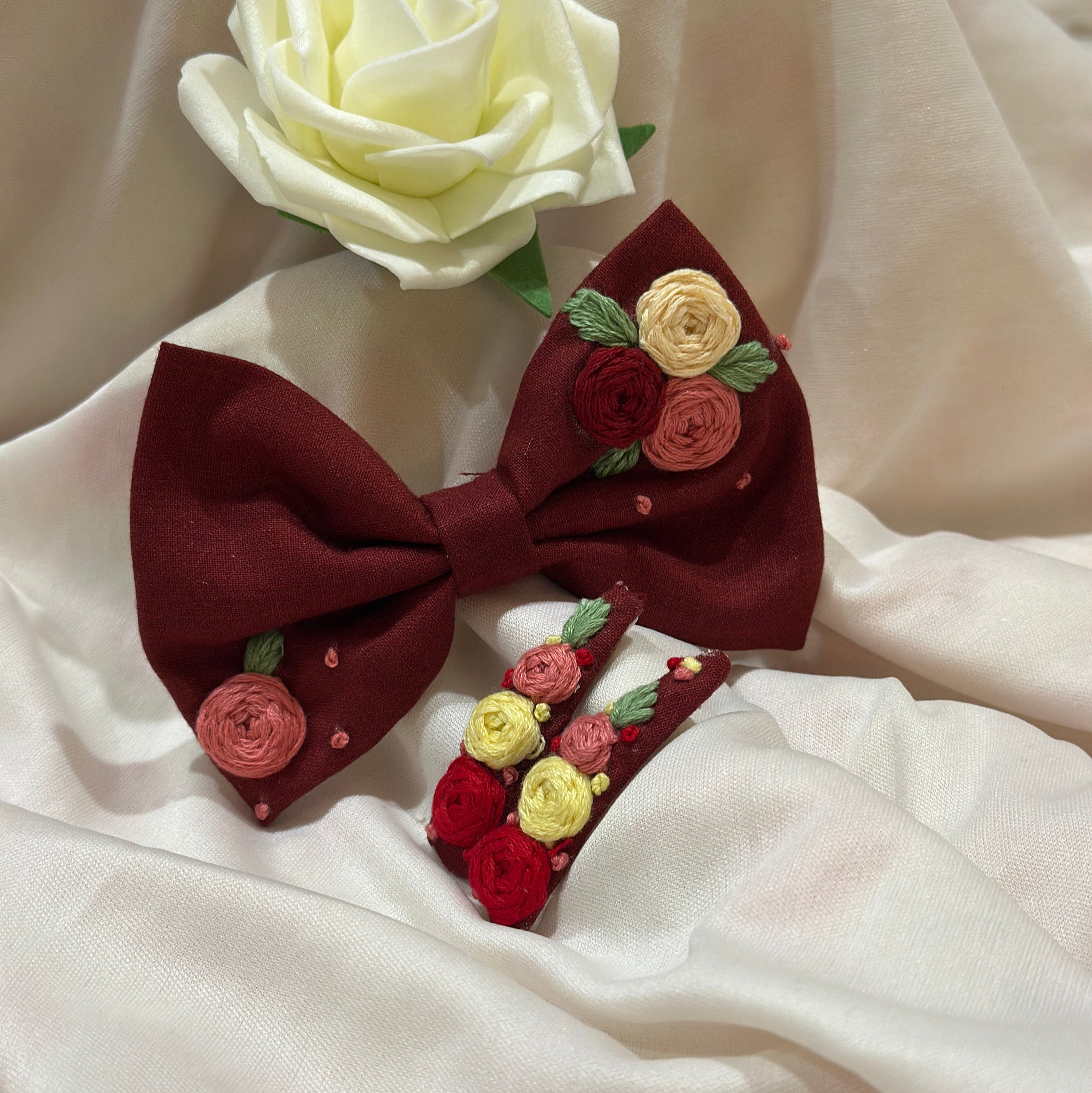 Handmade embroidered floral hair bow in crimson red and matching hair clip set featuring artisan rose embroidery and botanical detailing, beautifully crafted for gifting and special occasions.