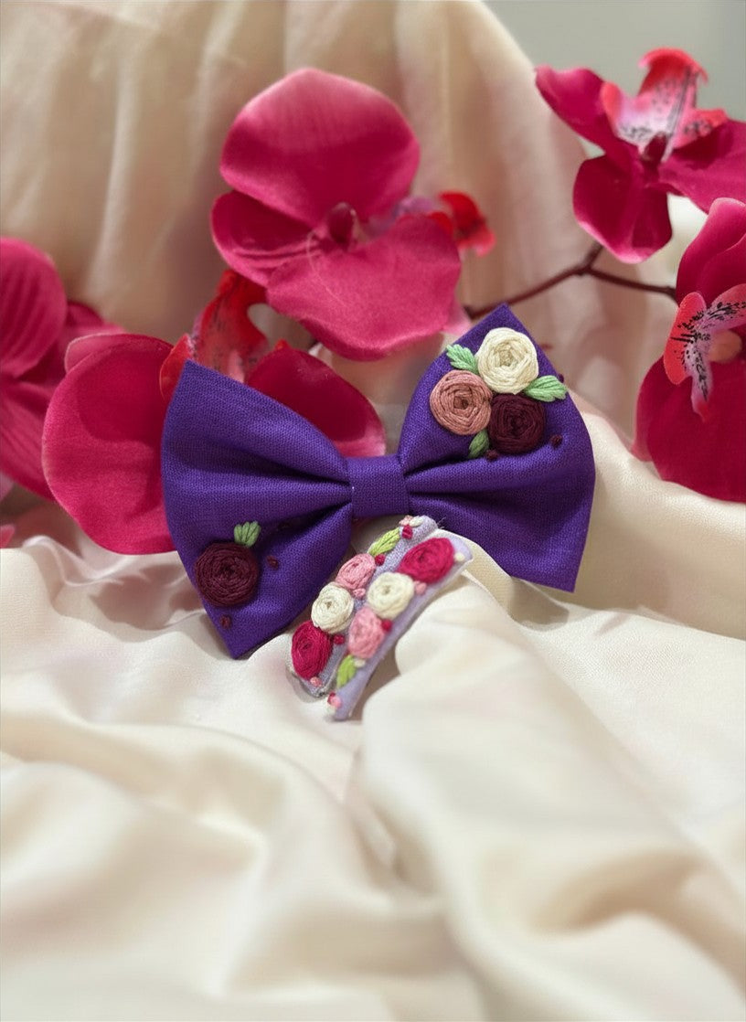 Handmade embroidered floral hair bow in royal violet and matching hair clip set featuring artisan rose embroidery and botanical detailing, beautifully crafted for gifting and special occasions.