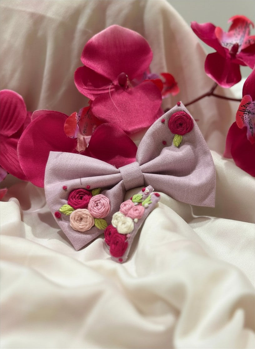 Handmade embroidered floral hair bow in soft pink and matching hair clip set featuring artisan rose embroidery and botanical detailing, beautifully crafted for gifting and special occasions.