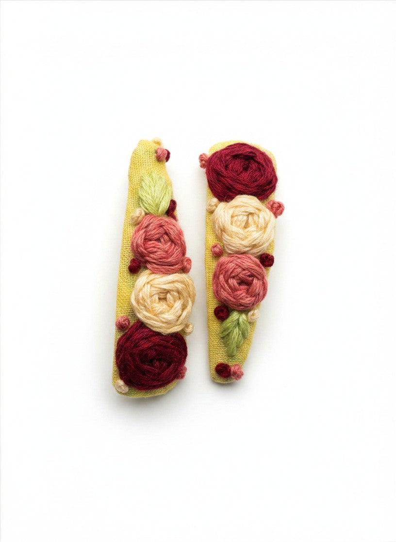Close-up of hand embroidered three-dimensional rose cluster on artisan hair clip in crimson and cream cotton thread