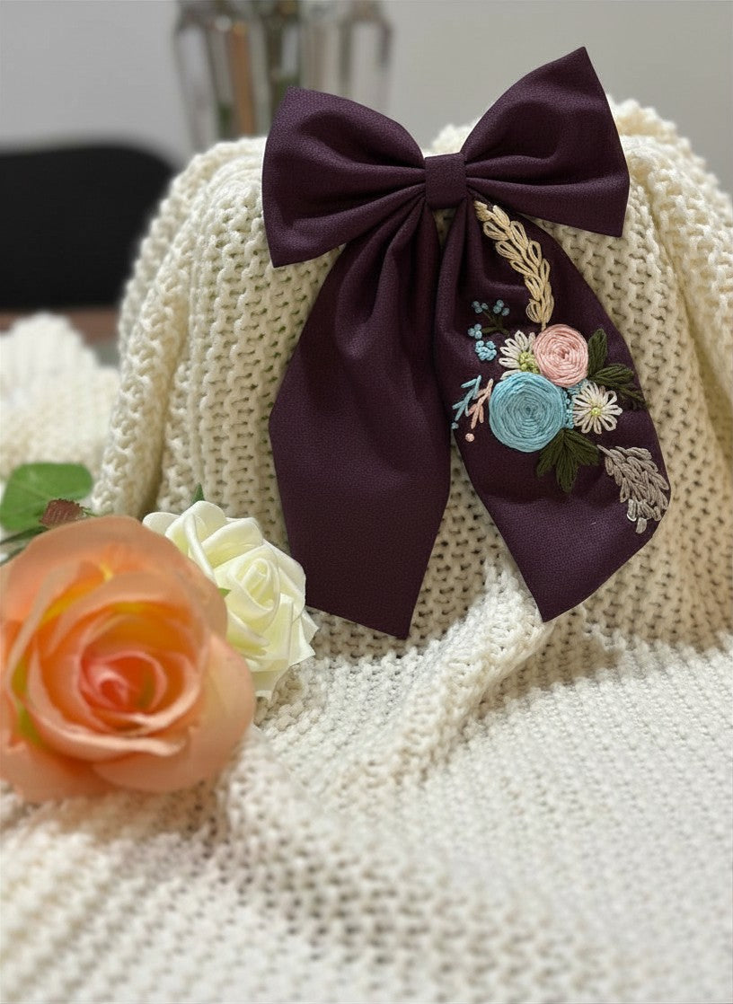 Hand embroidered floral pigtail bow in crimson burgundy fabric featuring artisan floral stitching and alligator clip attachment for girls' hairstyles