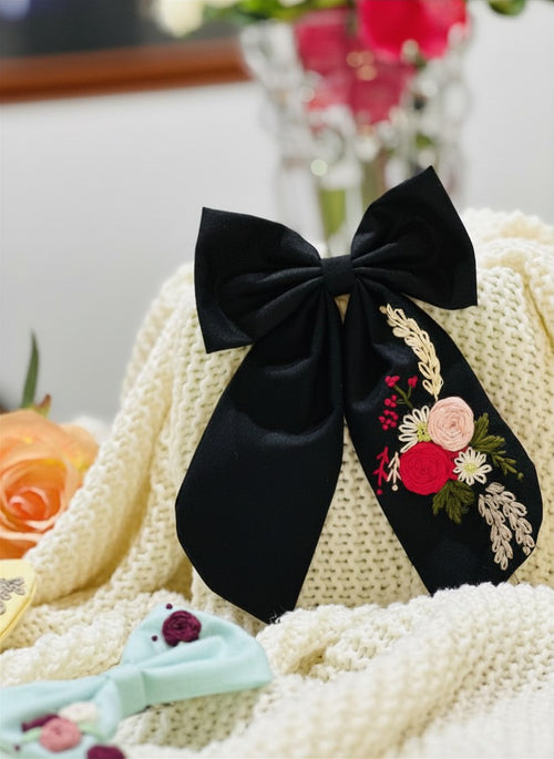 Hand embroidered floral pigtail bow in black dark as night cotton fabric featuring artisan floral stitching and alligator clip attachment for girls hairstyling.