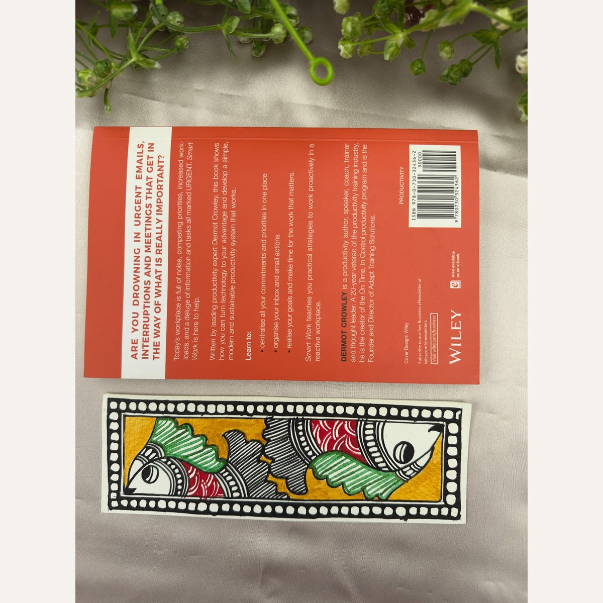 Hand-painted Madhubani Golden Currents bookmark featuring two crimson-red fish with green fins on a golden-yellow background, beside a book for size reference. Book not included.