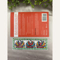 Hand-painted Madhubani Rainbow Fins bookmark featuring three fish with colourful fan-like fins and a green border with white dots, beside a book for size reference. Book not included.