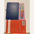 Hand-painted Madhubani peacock bookmark with purple and orange birds, a long crimson-red plume, turquoise background and pink dotted border, beside a notebook and book for size reference. Book and notebook not included.