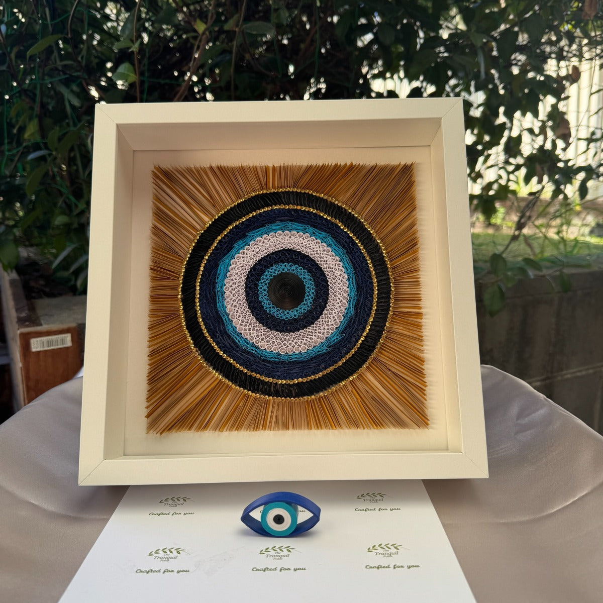 Handcrafted evil eye protection wall art made with dimensional paper quilling in a white frame
