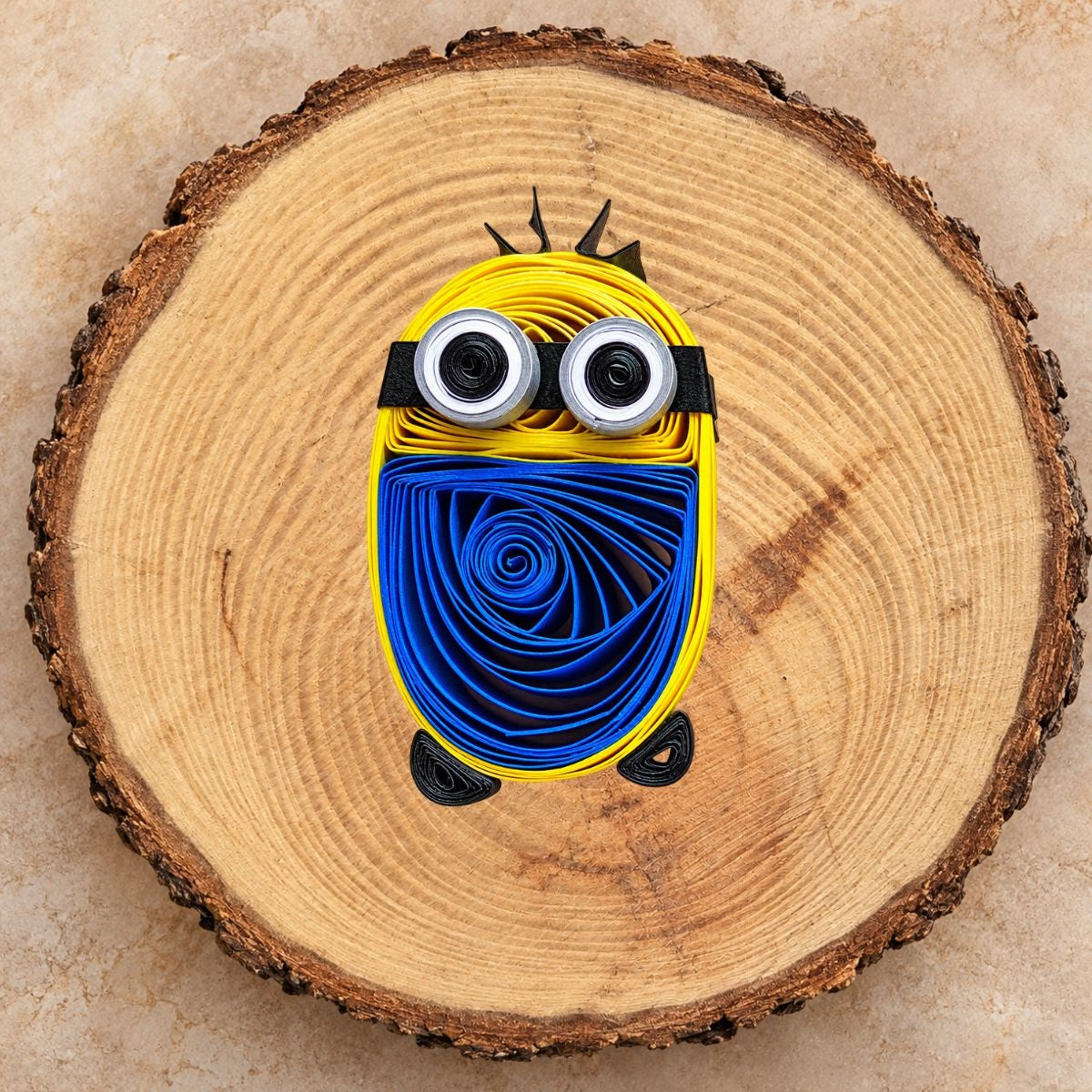 Handcrafted two-eye paper quilling character fridge magnet displayed on a natural wood slice.