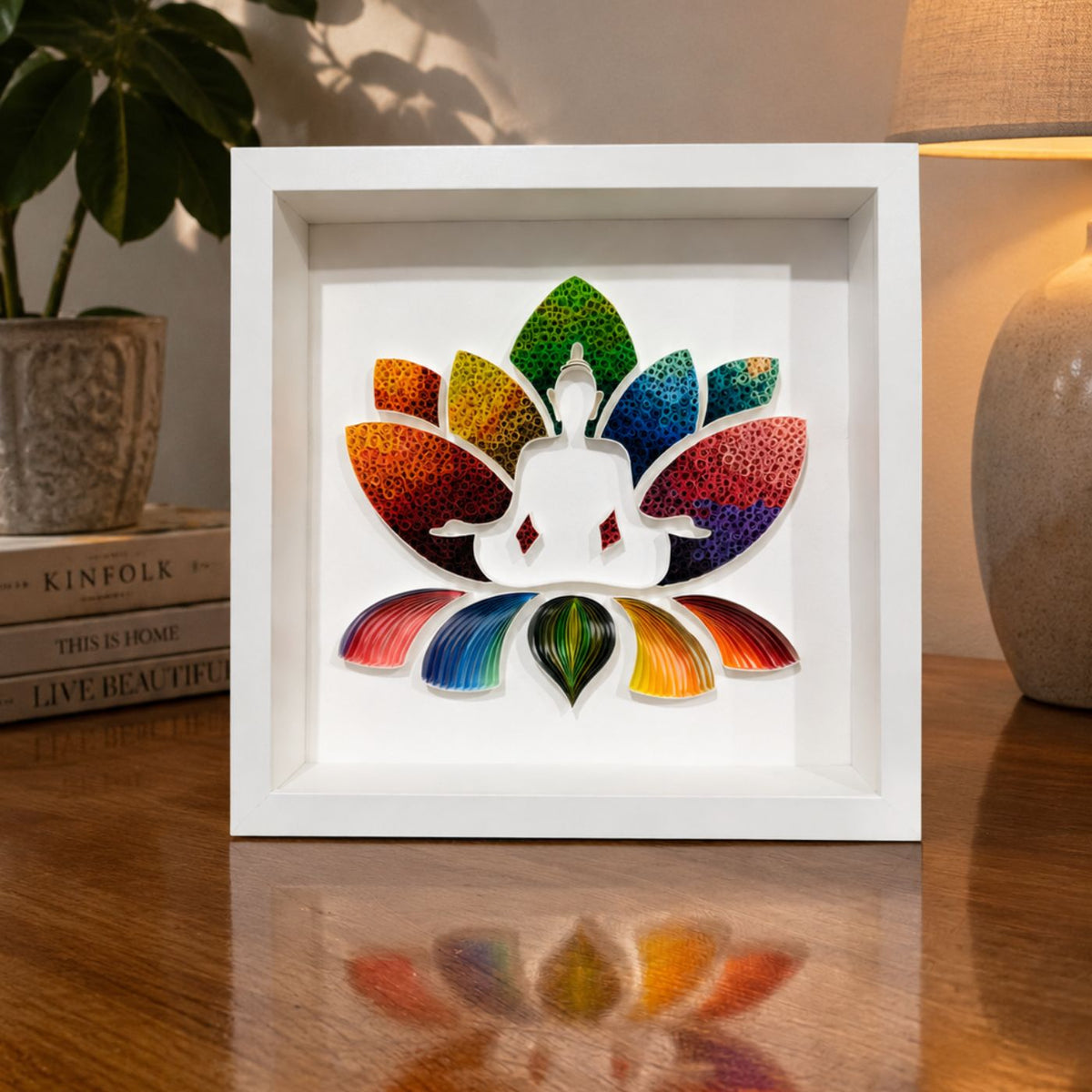 Handcrafted rainbow Buddha paper quilling wall art featuring a meditating Buddha seated within a colourful lotus flower in a white shadow box frame, 25 x 25 cm original artwork.