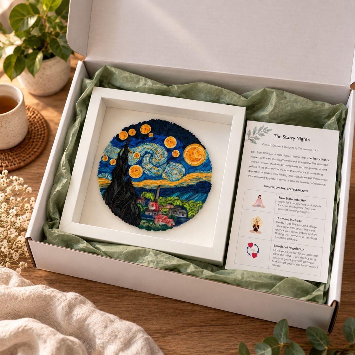 Close-up of handcrafted Starry Night paper quilling art showing swirling blue paper coils and luminous yellow stars in a white gift box wrapped in tissue and story card